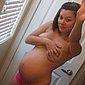 Schwangere junge Frau fotografiert sich selbst nackt